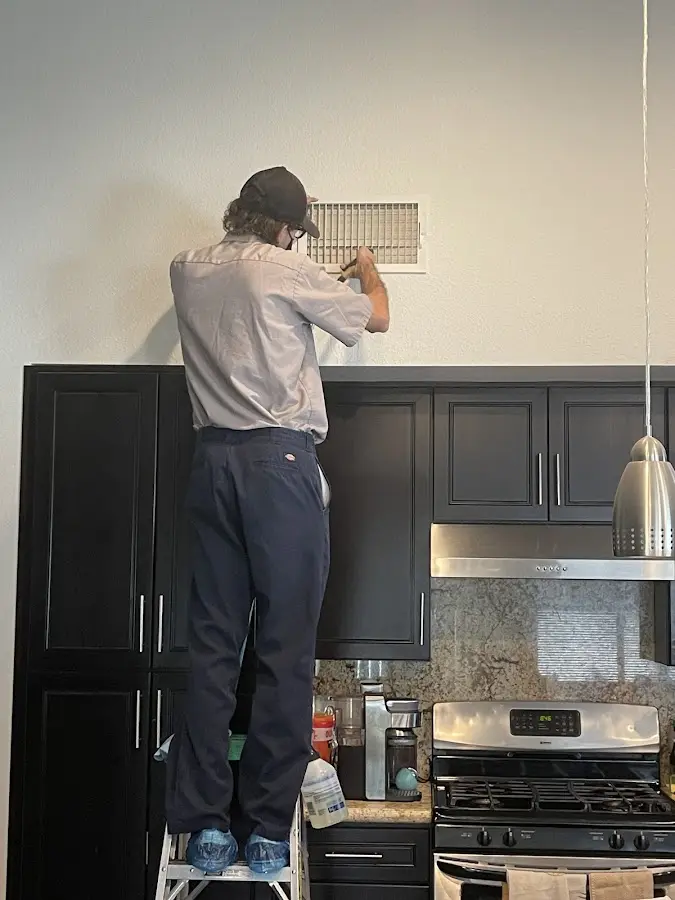 Technician inspecting an air vent during HVAC service in National City